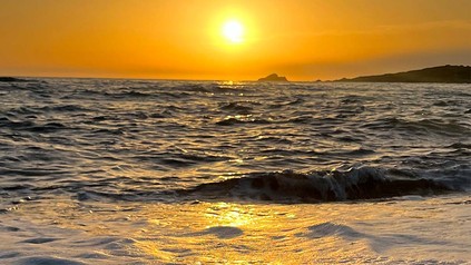 Aufnahme von Strand Richtung Wasser und Sonnenuntergang.