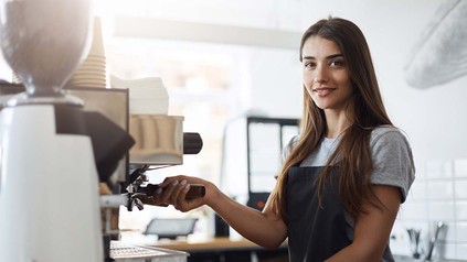 Studentische Aushilfe an der Café-Bar beim Zubereiten von Kaffee.