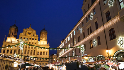 Aufnahme vom Augsburger Christkindlsmarkt mit Sicht auf Rathaus und Verwaltungsgebäude bei Nacht.