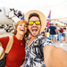 Junger Mann und junge Frau lachend in Sommerklamotten vor einem Flieger - machen gerade ein Selfie.