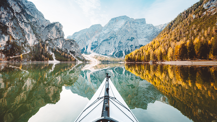 Spitze von Ruderboot auf See umgeben von Gebirgen.