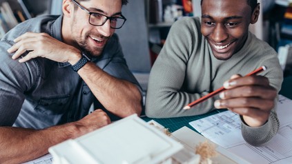 Zwei junge Männer sprechen über ein Architektur-Modell, das vor ihnen steht