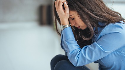 Junge Frau sitzt deprimiert auf dem Boden.